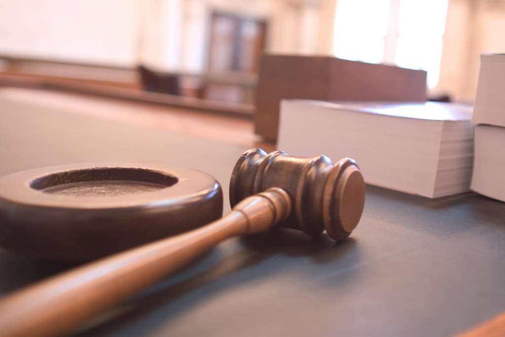 A judge's gavel and sounding block on a courtroom desk.